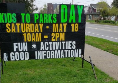 Garfield Park Neighborhood Association Kids to Park Day with a neon lettered black sign